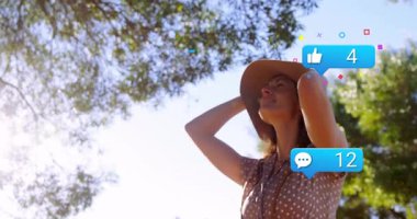 Parkta hasır şapka ayarlayan, yüzen kalp ve pazarlama için onay simgeleri sergileyen bir kadın. Doğa, açık hava, rahatlama, yaşam tarzı, yeşillik, yaz