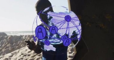 Sahilde beton direğin yanında duran bir adam akıllı telefon kullanarak AR ağı küresiyle teknolojiyi gösteriyor. Teknoloji, bağlantı, dijital, yenilik, açık hava, modern iletişim