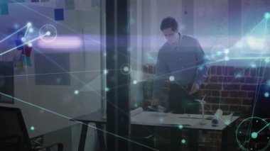 Mühendis, tasarım stüdyosundaki masanın üzerine eğilip beyaz tahta üzerinde ağ çizgileri olan planlar üzerinde çalışıyor. Mimarlık, yenilik, bağlantı, profesyonellik, çalışma alanı, teknik, yaratıcı