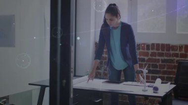 Stüdyodaki teknik planları inceleyen kadın mühendis dijital örtüler ve türbin modelini gösteriyor. Yenilik, sürdürülebilirlik, mimari, teknoloji, tasarım, gelecekçilik, işbirliği