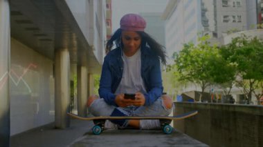 Şehir meydanında kaykay yapan bir kadın. Yüzen müzik ve teknoloji ikonlarıyla telefon ediyor. Kentsel, yaşam tarzı, minimalist, genç, sokak giyimi, çağdaş, eğlence amaçlı