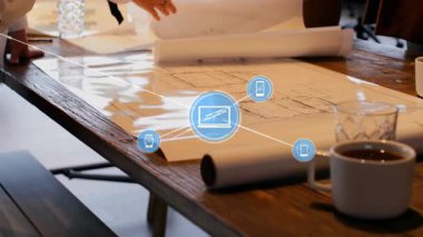 İki erkek meslektaşı kahve fincanları ve ağ simgeleriyle masanın etrafındaki mimari planları inceliyor. İşbirliği, takım çalışması, şehir tasarımı, modern ofis, dijital bağlantı, profesyonel toplantı, yaratıcı planlama