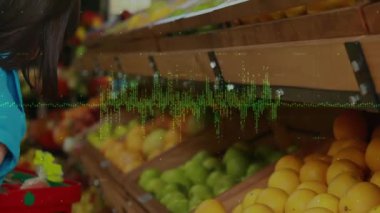 Kadın, dijital dalga boyu kaplamalarıyla perakende mağazasında narenciye tutarken öne eğiliyor. Taze ürün, perakende satış, sağlıklı yaşam tarzı, doğal gıdalar, canlı renkler, tüketici etkinliği, organik atmosfer