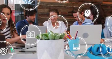 İş yerindeki iş arkadaşları, dizüstü bilgisayarların üzerinde yüzen dijital simgelerle masanın etrafında iş birliği yapıyorlar. İşbirliği, takım çalışması, yenilik, strateji, beyin fırtınası, modernlik, üretkenlik