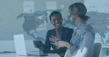 Masada iş planlarını tartışan iki bayan meslektaşımız dijital dünya haritası ve UI örtüleri gösteriyorlar. İşbirliği, beyin fırtınası, teknoloji, yenilik, kurumsal, profesyonel, iletişim