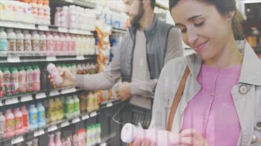 Süpermarket koridorunda üzerinde yüzen fiyat etiketleri olan buzlu içecek raflarına bakıyorlar. Bakkal, perakende, tüketim, modern, canlı, yaşam tarzı, sağlık