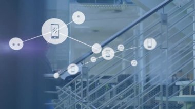 İş arkadaşları teknoloji ofisinde merdivenlerden yukarı çıkıp, parlayan akıllı telefonları ve müzik notaları ikonlarını gösteriyorlar. İşbirliği, dijital, bağlantı, modernlik, iş, yenilik, takım çalışması