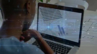 Teknoloji atölyesinde dizüstü bilgisayarda yazı yazan kadın tasarımcı, yüzen grafikler gösteriyor. Yaratıcılık, yenilik, üretkenlik, modern, profesyonel, fütüristik, çalışma alanı