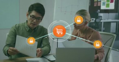 Teknik ofisteki iki danışman dijital alışveriş arabası ve kilit kaplaması raporlarını inceliyor. İş, işbirliği, teknoloji, siber güvenlik, veri, profesyonellik, yenilik