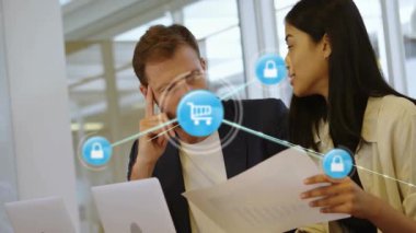 Kadın ve erkek masa başında kağıtları inceliyor, ecommerce güvenliğine el arabası ve kilit simgeleriyle dikkat çekiyorlar. İş, işbirliği, yenilik, teknoloji, profesyonellik, modernlik, dijital