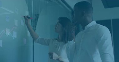 Modern ofisteki cam duvara, üzerinde yüzen çizgilerle satış grafiği çizen iki meslektaş. İşbirliği, beyin fırtınası, analitik, strateji, profesyonel, takım çalışması, yenilik