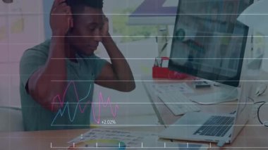 Kulaklık takan bir adam modern ofis masasında yazı yazıyor, animasyon finans çizelgeleri gösteriyor. Profesyonel, teknoloji, modern, çalışma alanı, odaklanma, dijital, üretkenlik