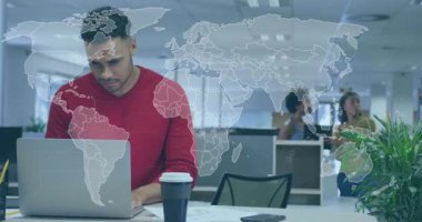 Kırmızı kazaklı bir adam şirket ofisinde dizüstü bilgisayarda çalışıyor, şeffaf bir dünya haritası var. Teknoloji, işbirliği, yenilik, çalışma alanı, profesyonel, modern, iletişim