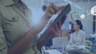 Teknoloji ofisinde tablet tutan kadın, akıllı telefon ve çalışan ekibin yanında yüzen müzik ikonları. İşbirliği, bağlantı, modernlik, dijital iletişim, takım çalışması, canlı, üretkenlik