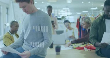 Tasarım ekibi, modern stüdyodaki çizimleri ve kumaşları yüzen veri grafikleriyle inceliyor. İşbirliği, yaratıcılık, moda, yenilik, çalışma alanı, endüstri, beyin fırtınası
