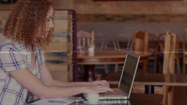 Kafede dizüstü bilgisayar ve akıllı telefon kullanan, animasyon teknoloji ikonları ve grafik örtüleri olan bir kadın. Rahat, modern, profesyonel, yaşam tarzı, çalışma alanı, sıcak, gündelik.