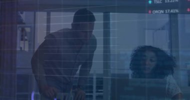 Kadın mali grafiklere odaklanırken, adam masana eğilip ofiste dizüstü bilgisayarı işaret ediyor. İş, işbirliği, analitik, veri, anlayış, takım çalışması, yenilik