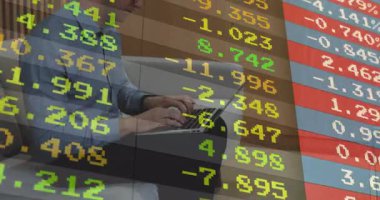 Ofis odasındaki gri koltukta dizüstü bilgisayarda yazan bir adam. Akan hisse senedi numaralarını gösteriyor. Teknoloji, finans, çalışma alanı, profesyonel, dijital, veri, modern