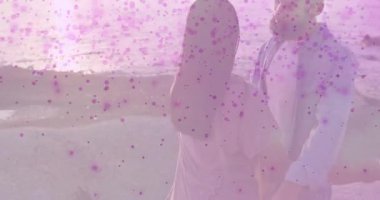 Günbatımı kumsalında kucaklaşan romantik çift, pazarlama için canlı pembe noktalarla deniz dalgaları sunuyor. Aşk, samimiyet, sükunet, romantizm, bağlantı, zarafet, sükunet