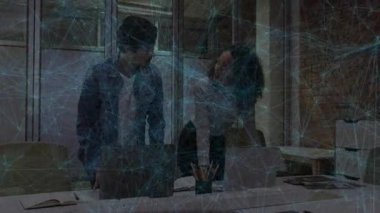 Kadın dizüstü bilgisayarı işaret ediyor ve erkek iş ofisinde üzerine yaslanıyor, üzerinde yüzen çizelge simgeleri var. İşbirliği, takım çalışması, modern, profesyonel, çalışma alanı, yenilik, beyin fırtınası