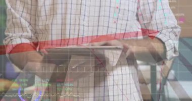 Adam tablet tutuyor ve kadın finans ofisinde yazı yazıyor, hareketli finansal grafikler gösteriyor. İş, takım çalışması, analitik, dijital, modern, üretkenlik, veri