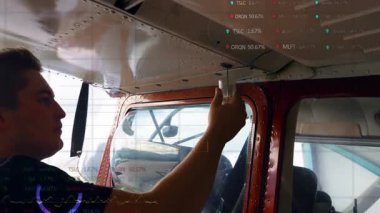 Pilot uçak kabinindeki cam kubbeyi kaldırıyor. İçinde canlı borsa saatleri grafikleri var. Havacılık, kokpit, mühendis, teknik, makine, endüstriyel, ulaşım