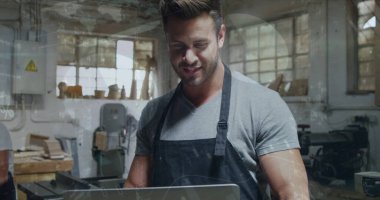 Atölyedeki ahşap tezgahta dizüstü bilgisayar kullanarak testere ve matkapla zanaatkârlığı inceliyorum. Esnaf, işçilik, marangozluk, sanayi, atölye, yenilik, el işi