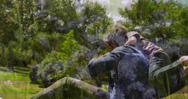 Gülümseyen baba ve oğul halka açık parkta oynuyor, çimenler, çalılar, yapraklı ağaçlar ve kirli patikalar. Aile, bağ, açık hava, eğlence, doğa, rahatlama, mutluluk.