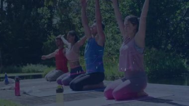 Grup, havuz kenarında yoga minderleri üzerinde diz çöküp hareketli fitness istatistikleriyle kollarını kaldırıyor. Sağlık, sükunet, ahenk, açık hava, fitness, farkındalık, doğa
