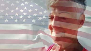 Okyanus kıyısında gülümseyen son sınıf öğrencisi kadın, pazarlama için animasyon Amerikan bayrağı taşıyor. Canlı, ilham verici, vatansever, sağlıklı, açık hava, boş zaman, güven