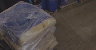 Düz mavi rafları gösteren turuncu elektrikli forklift ambalajlı bej palet. Sanayi, lojistik, makine, verimlilik, güvenlik, depolama, ulaşım