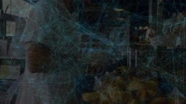 Olgun bir erkek müşteri fırın tezgahında ekmek somunlarını inceliyor ve üzerinde animasyon çizelgesi var. Esnaf, fırınlar, kırsal, sıradan, iç mekan, yemek, alışveriş