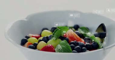 Beyaz seramik kasede çeşitli meyve dilimleri ve sosyal medya simgeleri var. Sağlıklı, canlı, taze, minimalist, renkli, besleyici, dijital