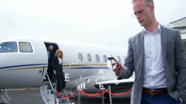 İş adamı, asfalt üzerindeki halat bariyerinin yanındaki akıllı telefonu animasyon durum haritasıyla kontrol ediyor. Lüks, profesyonellik, seyahat, şirket, elit, modern, şık