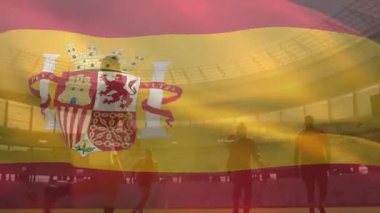 Futbol takımı topun etrafında toplanıyor, İspanyol bayrağı spor pazarında parlıyor. Sporcular, takım çalışması, yarışma, stadyum, spor, birlik, adrenalin