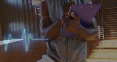 Olgun koç elinde kronometreyle spor salonunda, spor yapmak için neon kalp atışı grafiğini sergiliyor. Sporcu, antrenman, fitness, motivasyon, spor giyimi, zindelik, kararlılık