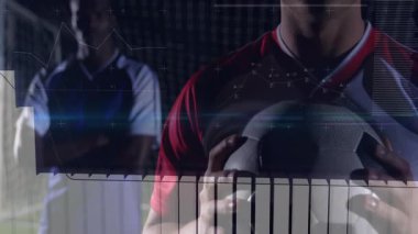 Kale ağıyla poz veren iki futbol takım arkadaşı bar çizelgeleri ve çizelgelerle spor analitiği sergiliyorlar. Sporcular, spor, fitness, takım çalışması, analitik, dijital, stadyum