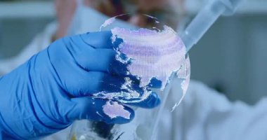 Maske takan kıdemli bilim adamı pipette holografik dünya projeksiyonu hakkında bilimsel veriler üzerinde çalışıyor. Araştırmacı, yenilik, biyoteknoloji, fütüristik, hassasiyet, keşif, görselleştirme