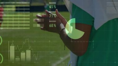 Yeşil önlük giyen futbolcu çimen sahasında koşuyor, spor analitiği dünya haritası grafiklerini gösteriyor. Sporcu, fitness, motion, outdoor, technology, analysis, competition