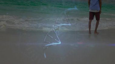 Kumsalda çıplak ayakla yürüyen bir adam holografik halkalarla teknoloji DNA sarmalı sergiliyor. Gelecekçi, yenilikçi, teknoloji, bilim, dijital, biyometrik, minimalist