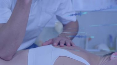 Erkek terapist, parlak klinikte hastaya terapi uyguluyor. Animasyon omurga grafiği gösteriyor. Sağlık, sağlık, rehabilitasyon, sağlık, manüel terapi, terapi, klinik