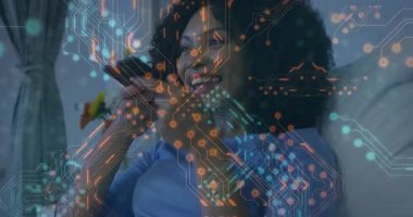 Akıllı telefonu ağzının yakınında tutan bir kadın devre grafikleri ve ayçiçekleri ile akıllı evi kontrol ediyor. Gelecekçi, teknoloji, konut, yaşam tarzı, yenilik, rahat, dijital