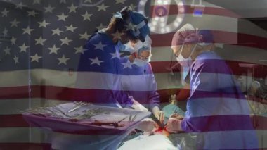 Tıbbi ekip yukarıdaki ışık altında ameliyat yapıyor, aletler ve hareketli Amerikan bayrağı sergiliyor. Cerrahi, sağlık, takım çalışması, klinik, hassasiyet, tıbbi, yenilik