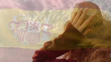 Hasır şapka tutan ve İspanyol bayrağıyla gün batımına doğru bakan bir kadın. Deniz manzarası, seyahat, rahatlama, canlı, manzaralı, doğa, sükunet