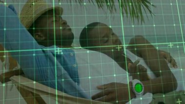 Çift, palmiye gölgesinde güvertede koltuğa yaslanarak sağlık teknolojisi şebekesini akıllı bir şekilde gösteriyor. Rahatlama, rahatlama, açık hava, tropik yaşam, refah, arkadaşlık, sükunet.