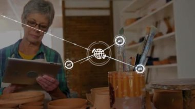 Usta kadın el sanatları atölyesinde kil çömlekler arasında tablet kullanıyor, dijital ağ bağlantısı gösteriyor. Sanatçı, yaratıcılık, kırsal, yenilik, zanaat, eğitim, vintage