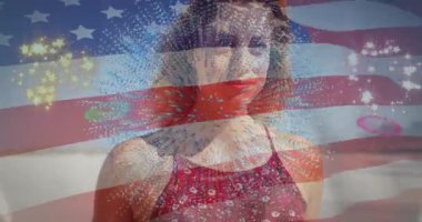Sahilde dikilen bir kadın, animasyon Amerikan bayrağı gösteriyor ve havai fişekler patlıyor, pazarlama teması. Vatansever, kutlama, neşeli, canlı, boş zaman, yaz, ilham verici.