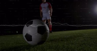 Erkek sporcu gece ıslak sahada duruyor, futbol topu etrafında teknoloji veri grafikleri gösteriyor. Stadyum, stadyum ışıklandırması, atletik, tek renkli, dijital, taktik, yarışma
