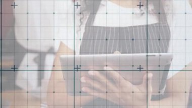 Ev mutfağında tarif çizelgesini üst üste koyarken tablet kullanan bir kadın yemek pişiriyor. Aşçılık, teknoloji, modern, yerli, yaşam tarzı, tasarım, aşçılık