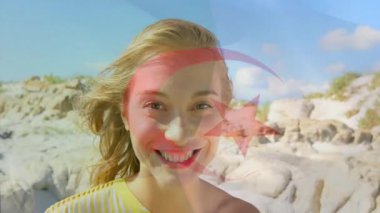 Kayalık sahil kıyısında duran bir kadın teknoloji temalı kırmızı hilal yıldız grafikleri sergiliyor. Doğa, manzara, açık hava, macera, dinginlik, canlılık, minimalizm